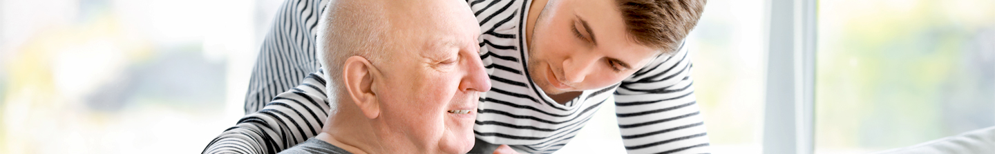 A young male caregiver talking with the elderly man he cares for
